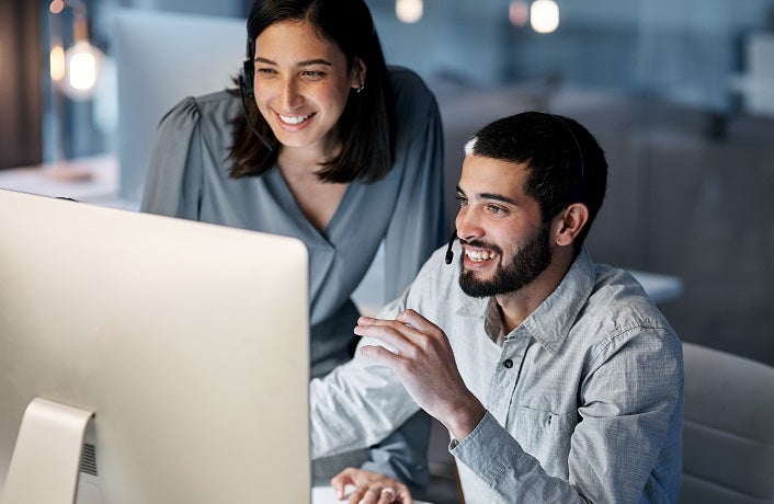 Call center, manager and happy team at computer for software training, customer service and CRM in office. Man, woman and sales mentor helping intern on desktop, telemarketing and technical support.